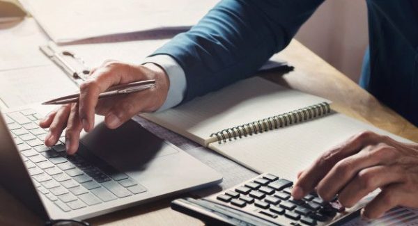 Workig del hombre de negocios y que usa la calculadora con el ordenador portátil en el escritorio _ Foto Premium